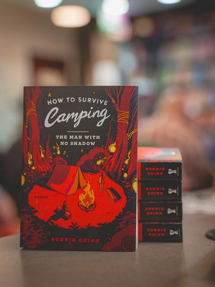 How to Survive Camping by Bonnie Quinn displayed beside a stack of signed copies