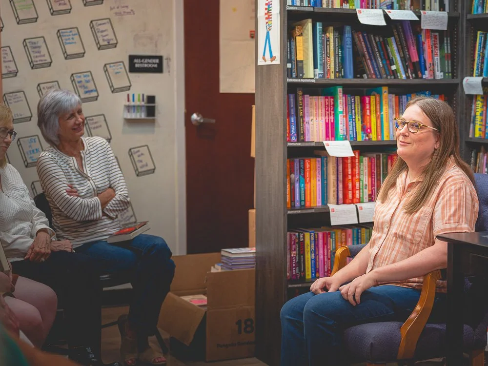 Bonnie Quinn speaking with readers seated beside the bookstore shelves