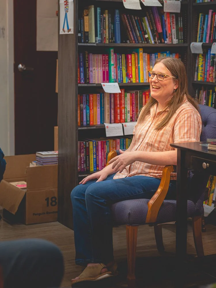 Bonnie Quinn smiling while speaking in front of colorful bookshelves