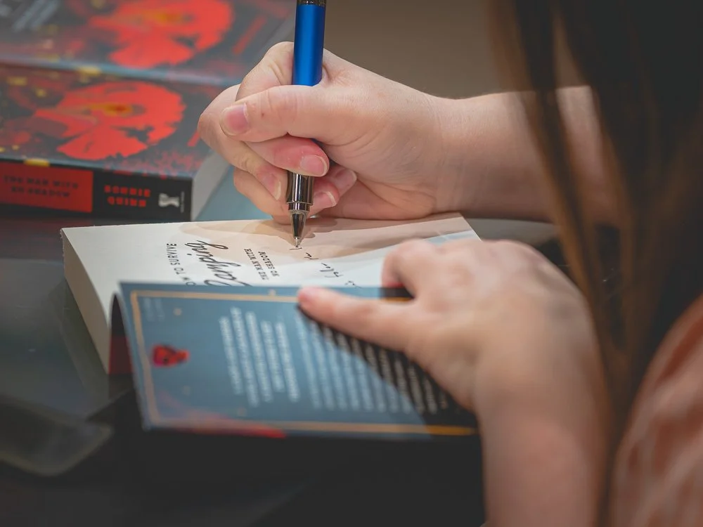 Close view of Bonnie Quinn signing a reader's book