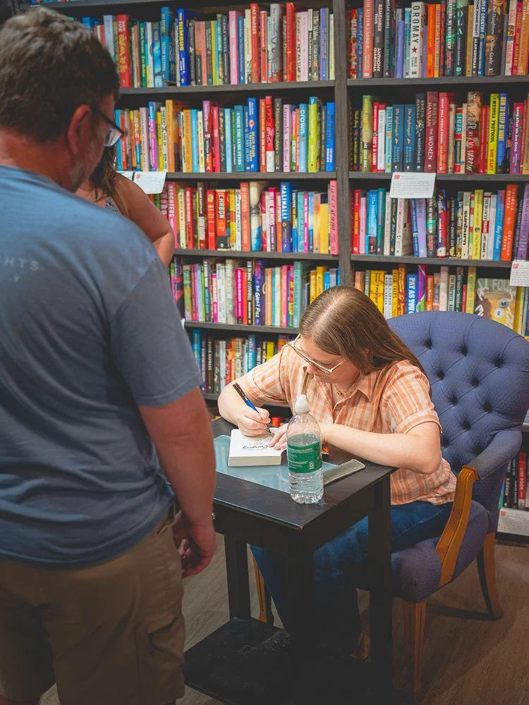 Bonnie Quinn signing a book for a reader at the event table