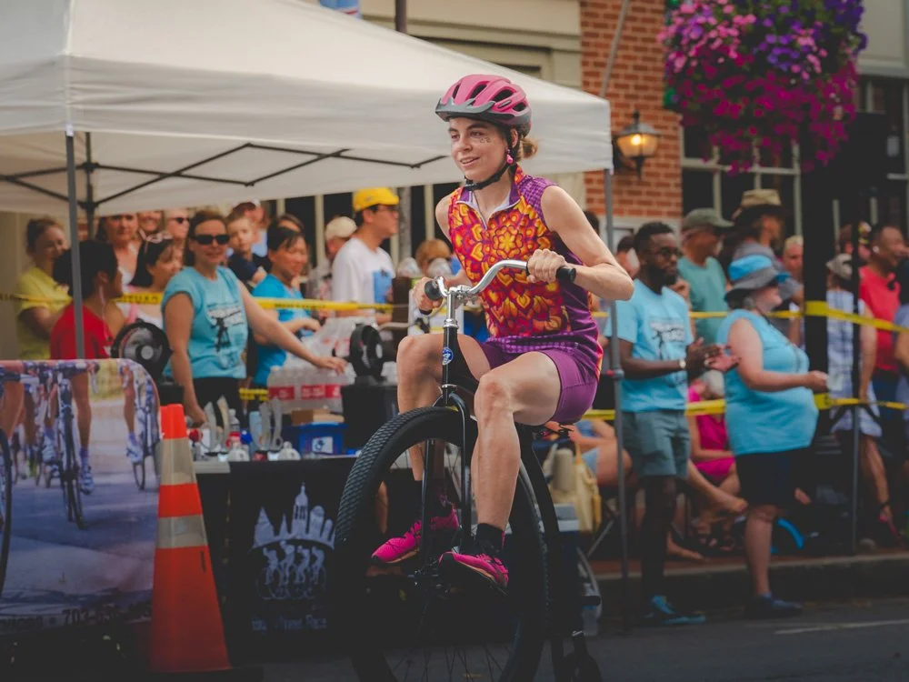 A rider in bright pink balancing on a small novelty bicycle during the race