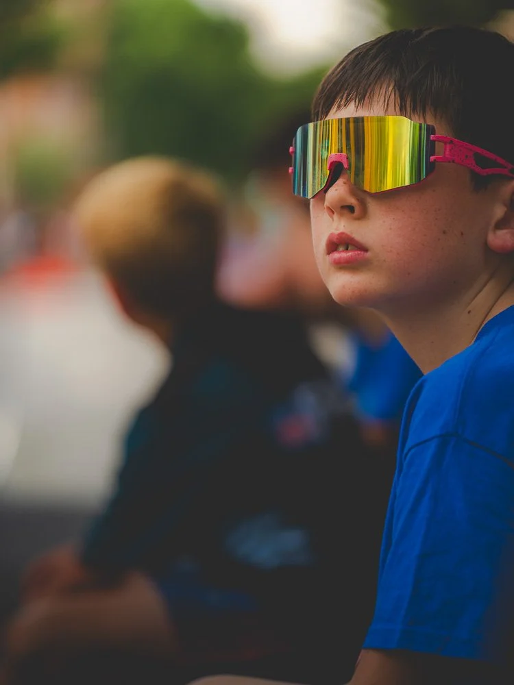 A young spectator in mirrored sunglasses watching the race