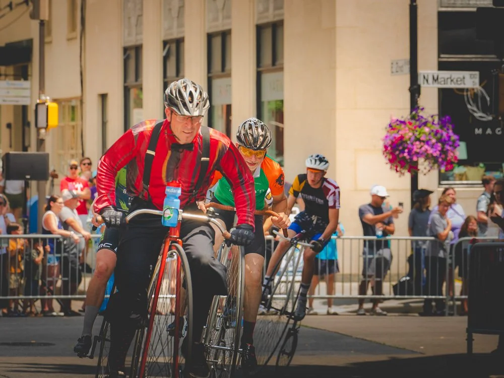 A group of high-wheel cyclists leaning through a downtown turn