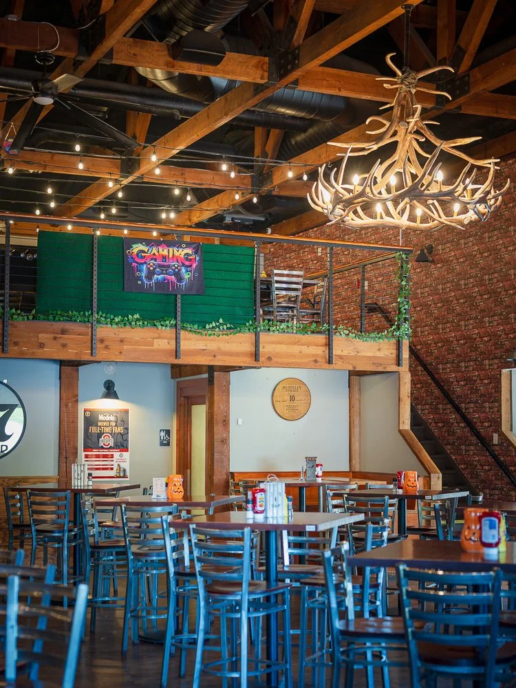 Liberty Social dining room beneath wood beams and an antler chandelier