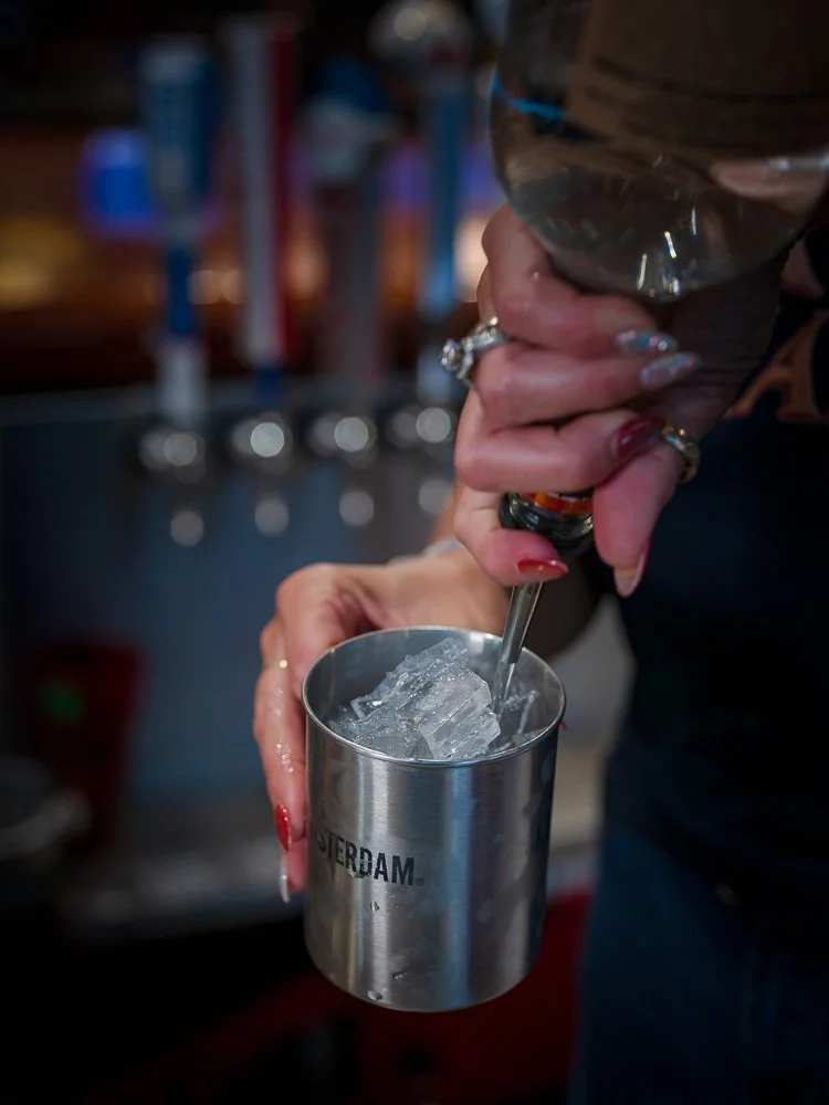 A bartender muddling a cocktail over ice