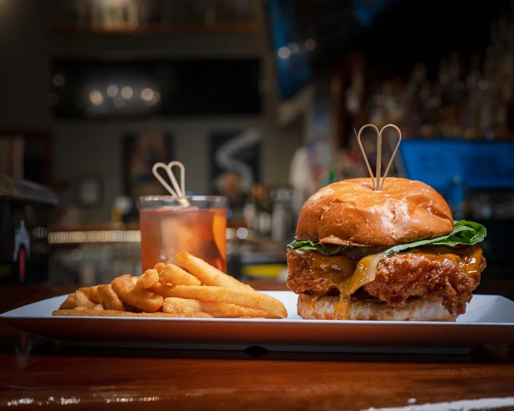 Fried chicken sandwich, fries, and a smoked Old Fashioned at the bar
