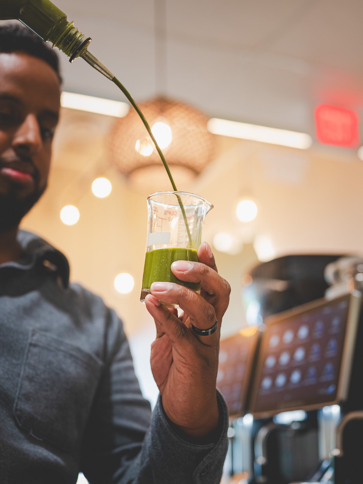A bartender pouring a vivid green mixture into a glass beaker