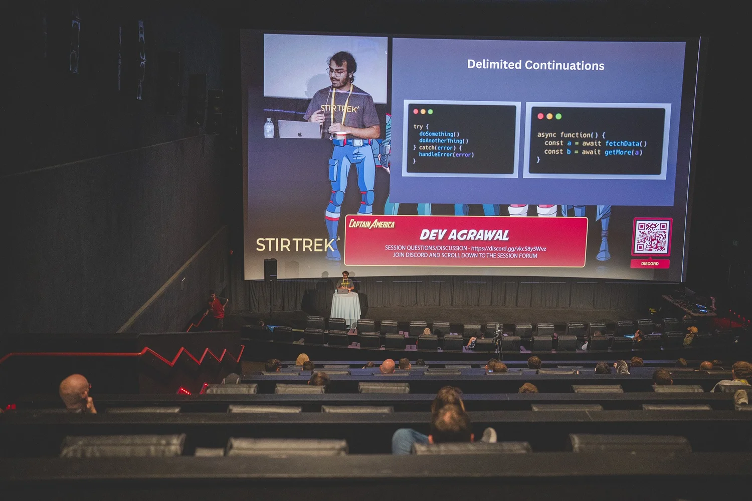 A technical speaker presenting to attendees inside an AMC theater